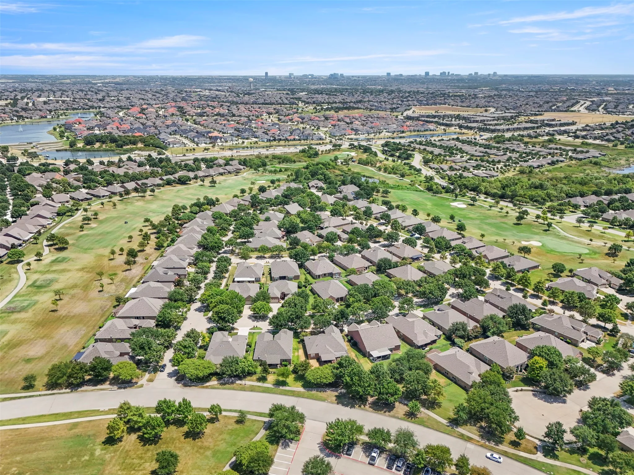 Expansive residential development with mature trees, a golf course, and a nearby body of water