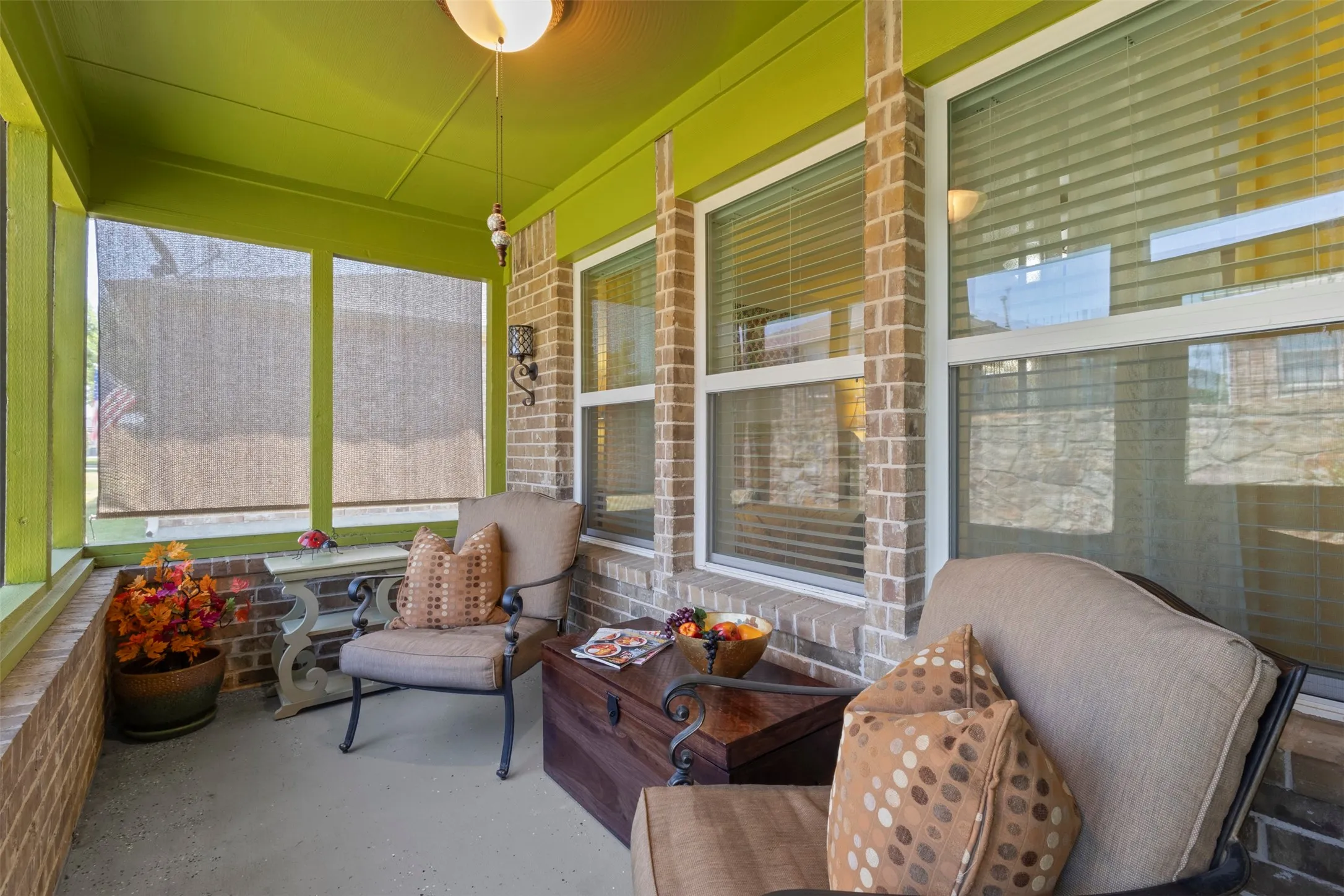 Screened porch featuring brick accents, recessed lighting, and a durable concrete floor