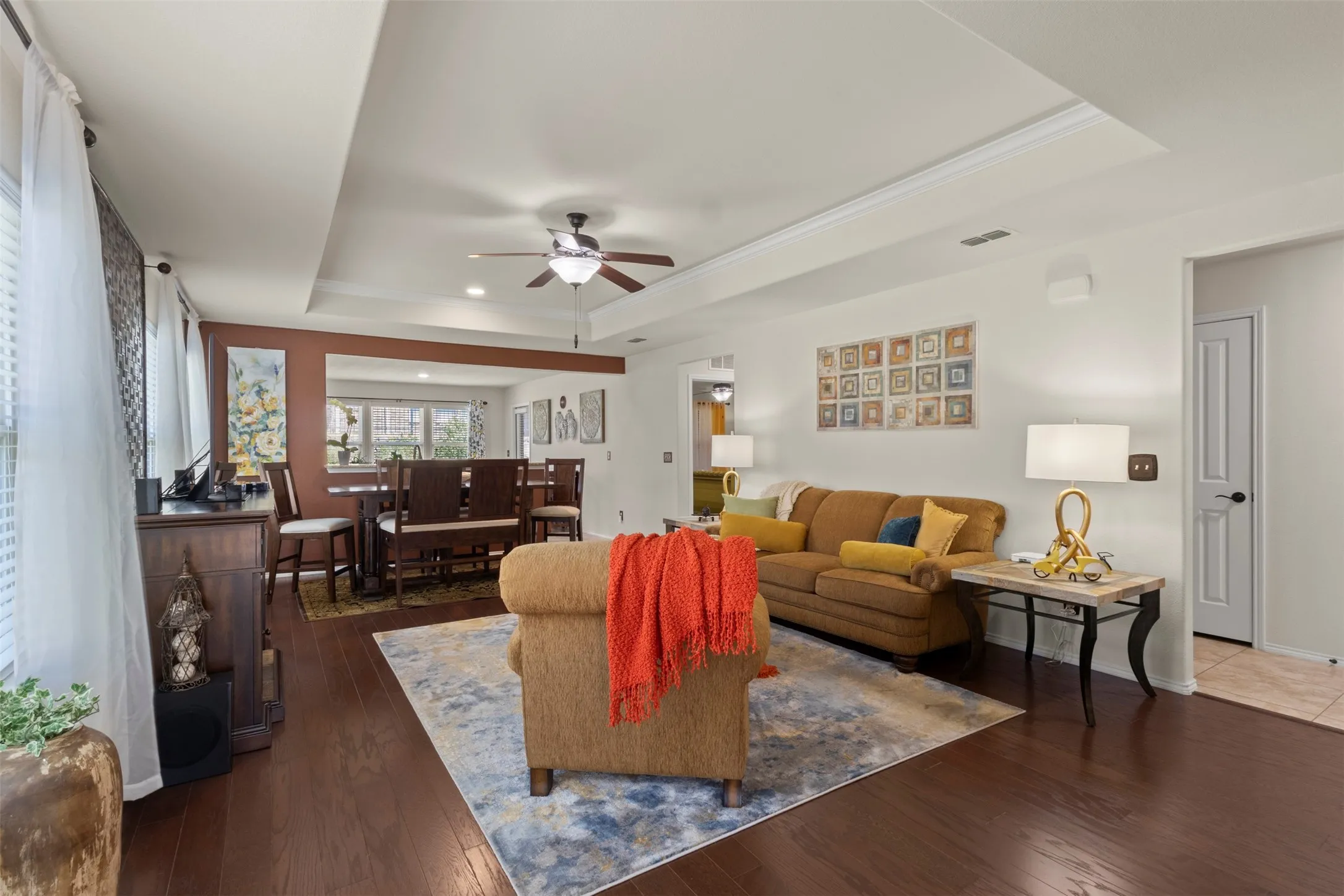 Recessed lighting, ceiling fan, rich wood-finish flooring, tray ceiling detail, and built-in window blinds