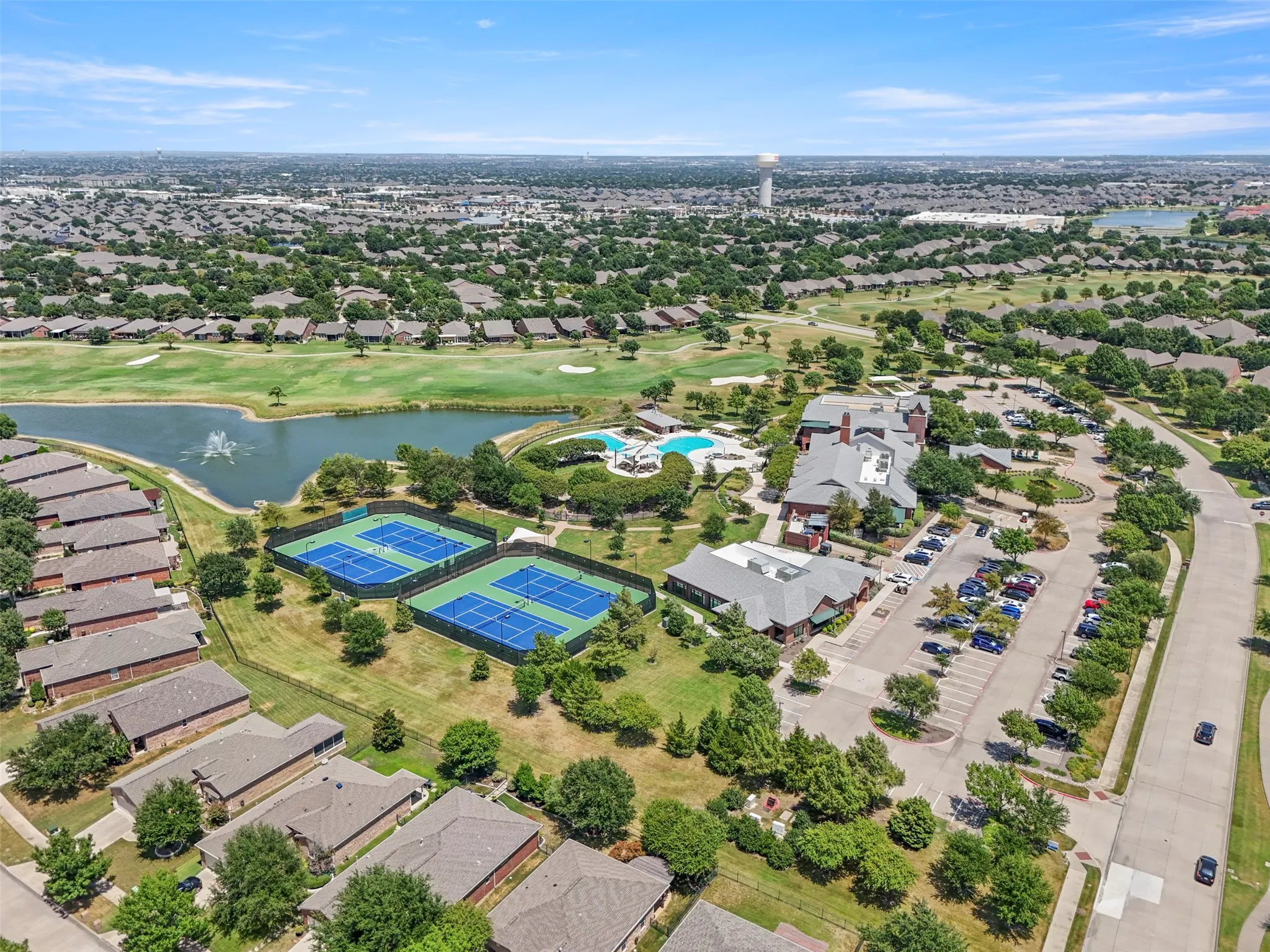 Community amenities featuring multiple tennis courts, a swimming pool with lounge areas, a golf course with a water feature, a clubhouse, and ample parking