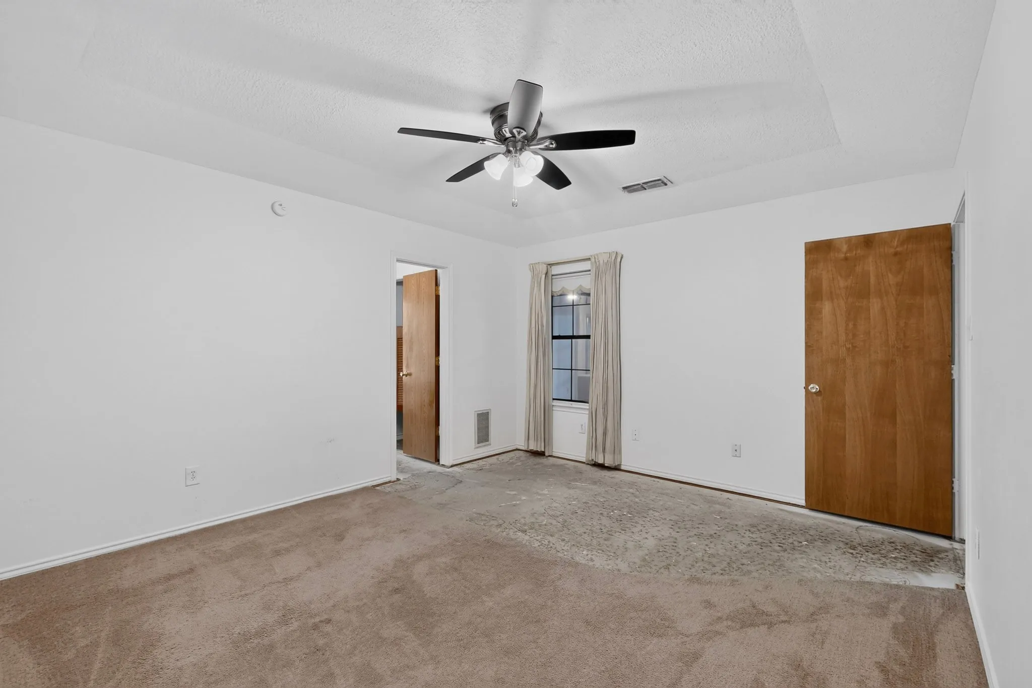 Carpeted room with white walls, a ceiling fan, and a single window