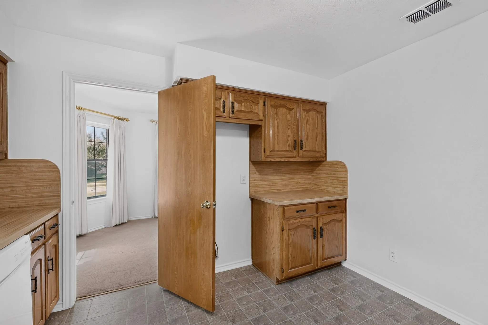 Kitchen featuring wood cabinetry, laminate countertops, and tile flooring