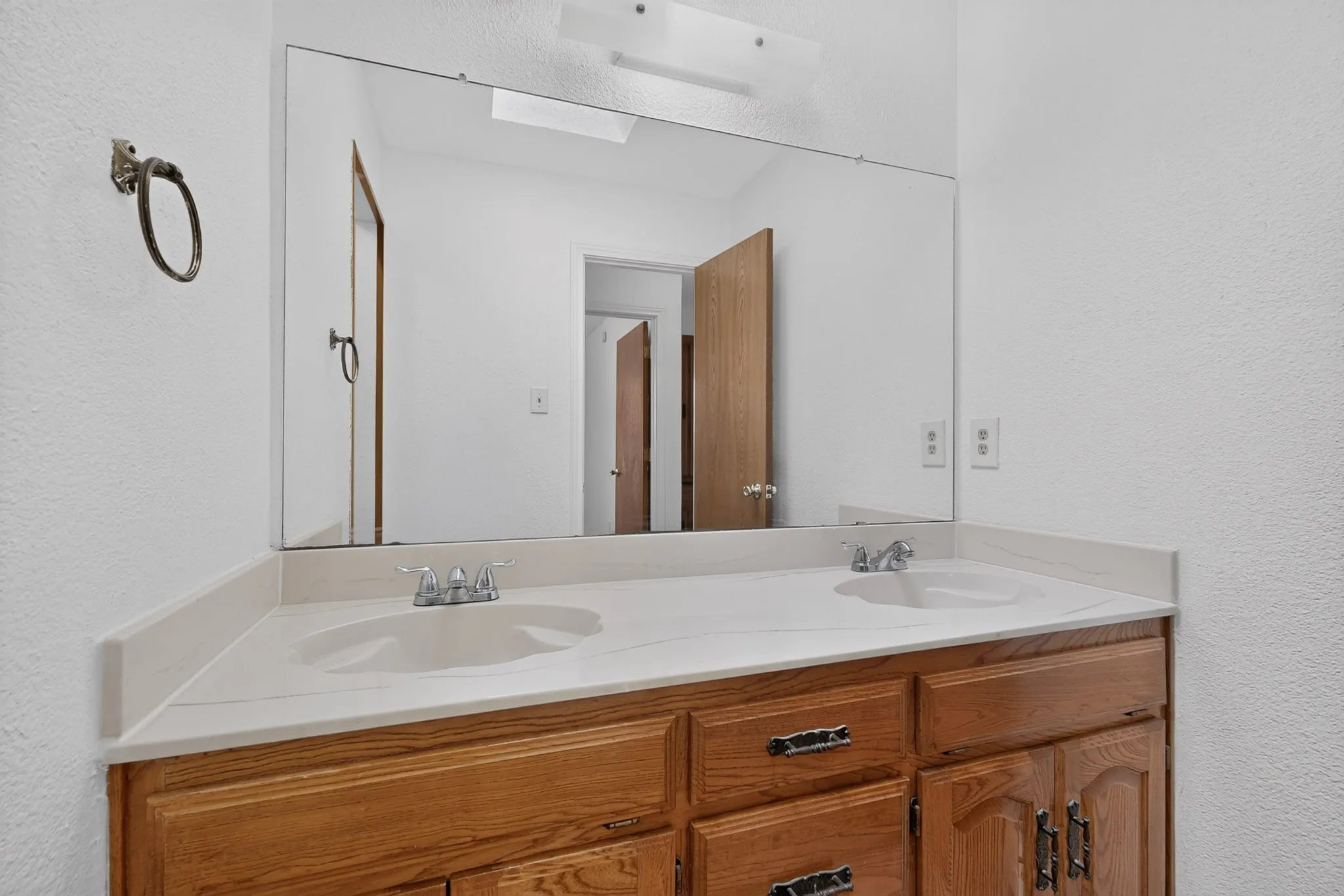 Dual vanity with integrated sinks, wood-finish cabinetry, and a full-width mirror
