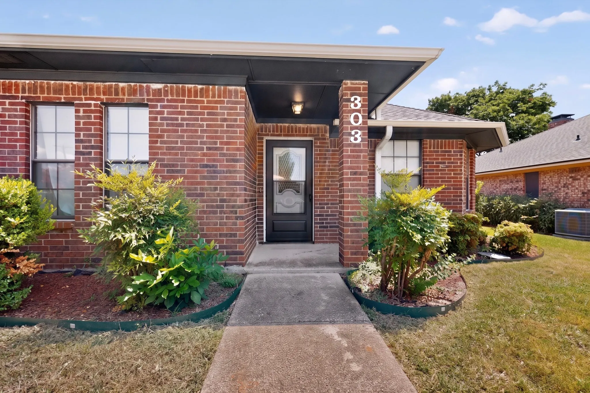 Brick exterior with covered entry and concrete walkway