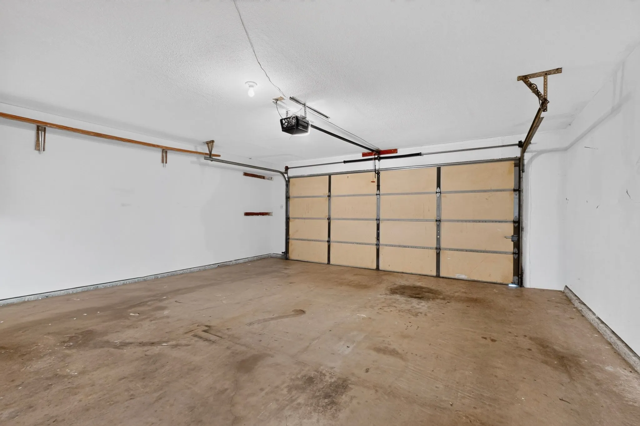 Attached garage featuring a concrete floor, automatic garage door opener, and overhead lighting