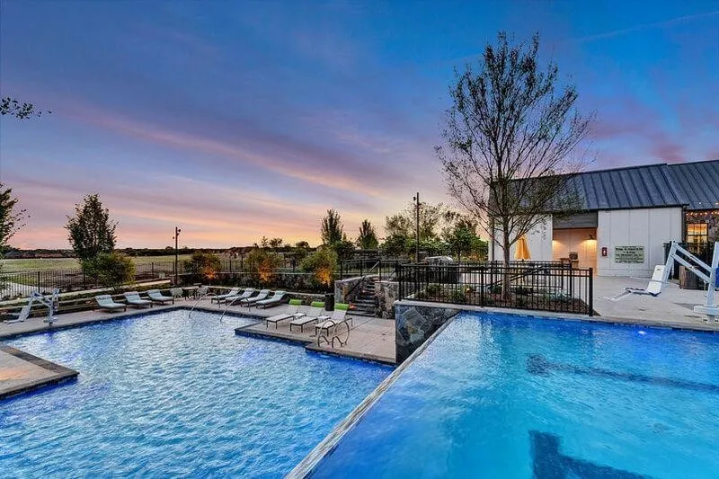 Expansive swimming pool with an integrated infinity edge, surrounded by a stone-accented deck