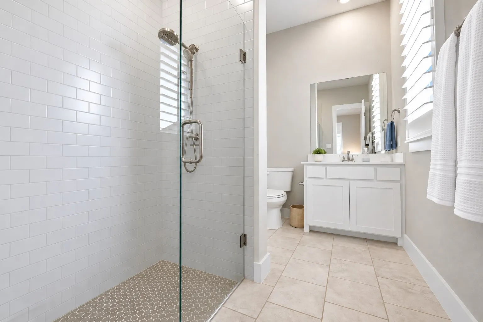 Glass-enclosed shower with subway tile surround and hexagonal tile flooring