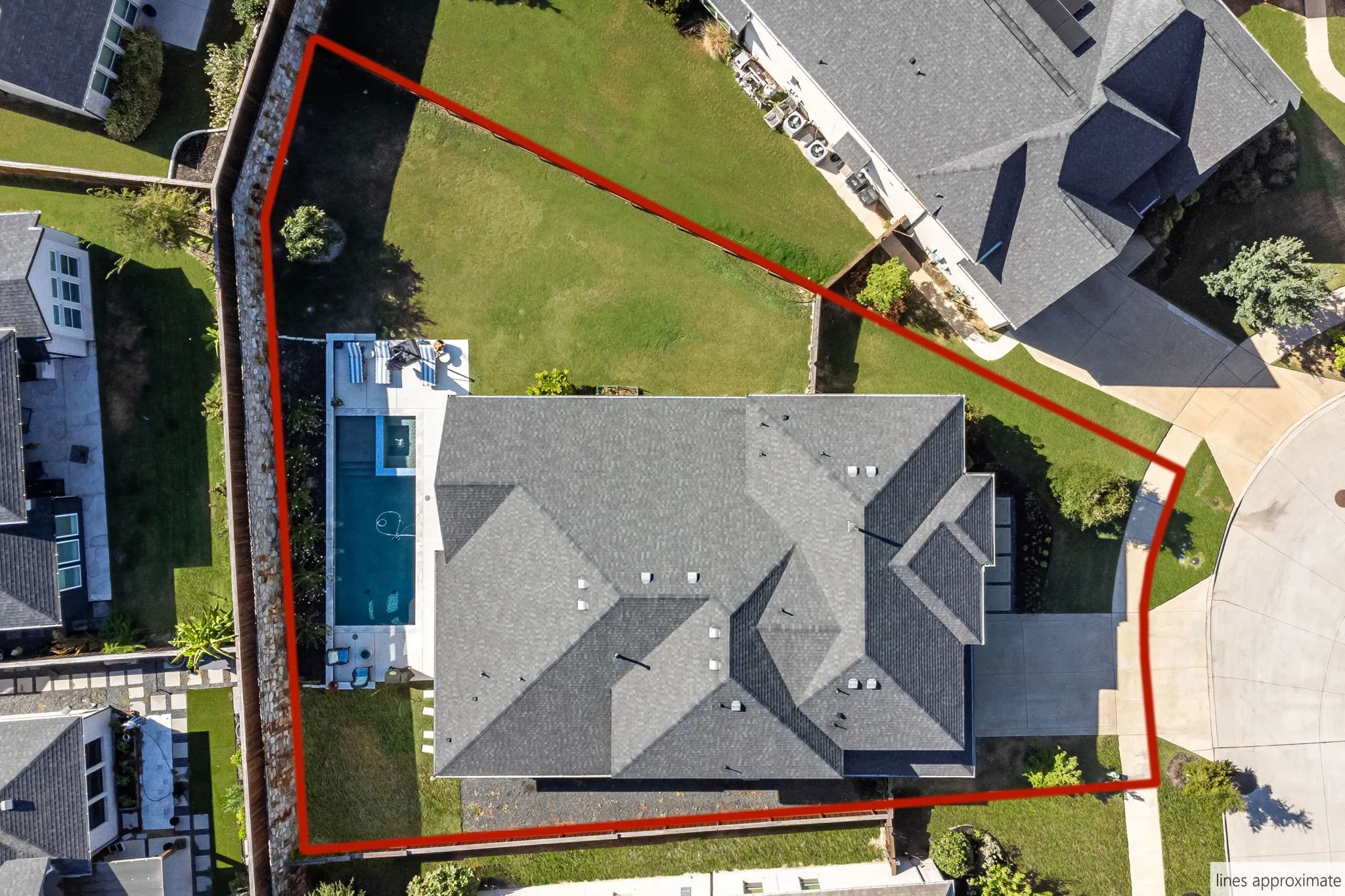 Expansive lot featuring a structured pool with integrated spa, concrete patio, and a manicured lawn