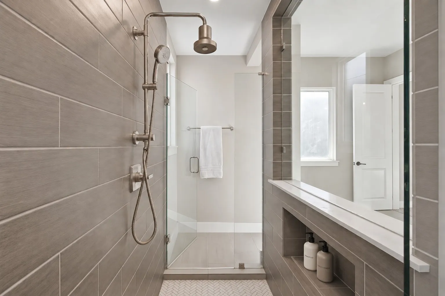 Walk-in shower with full glass enclosure, rainfall showerhead, and a built-in shelving niche with a stone surface