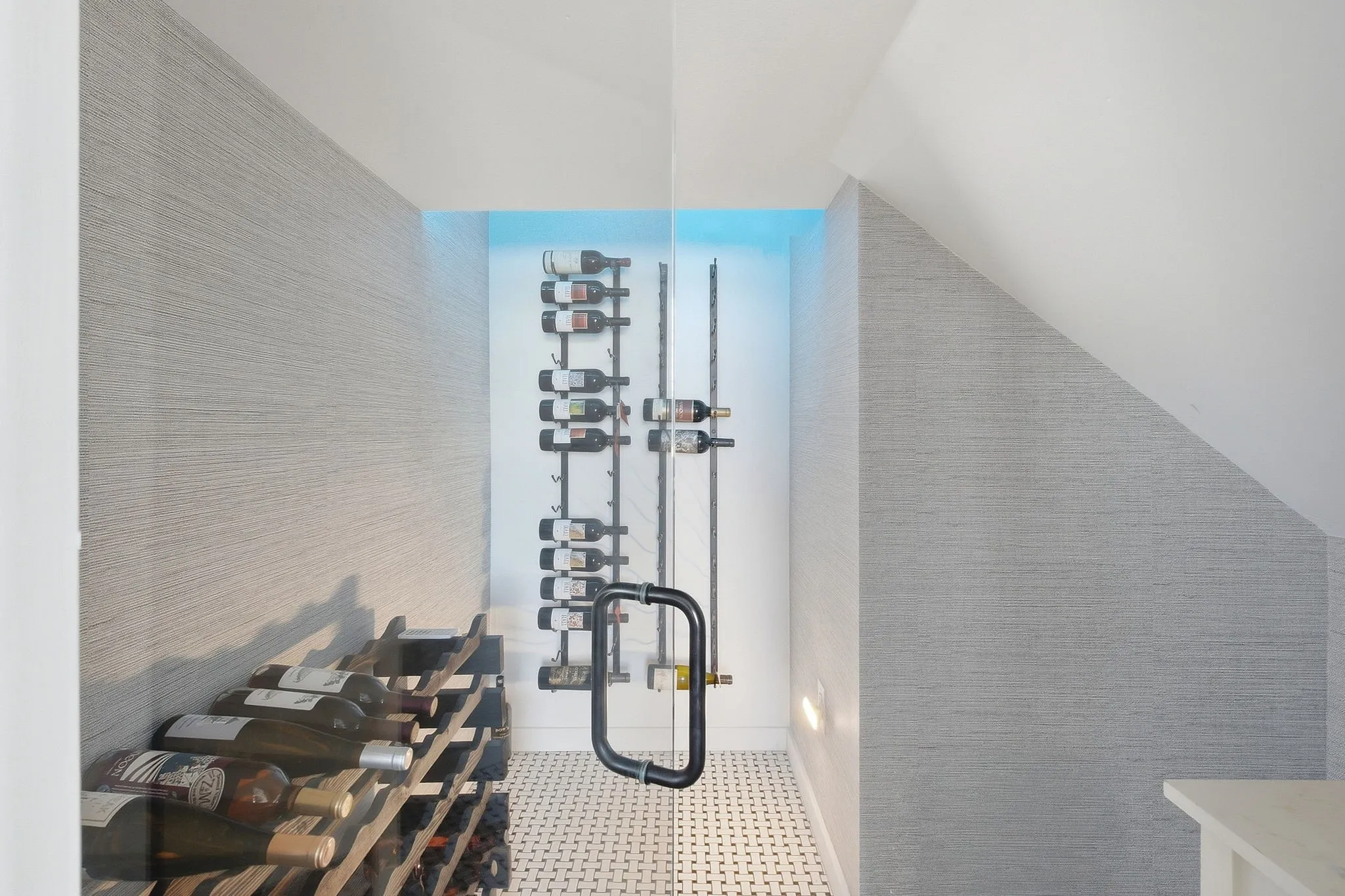 Glass-enclosed wine storage with custom racks, textured wall covering, and tiled flooring