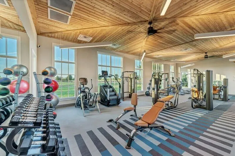 Fitness center featuring a vaulted wood-paneled ceiling, large windows, ceiling fans, and various exercise equipment