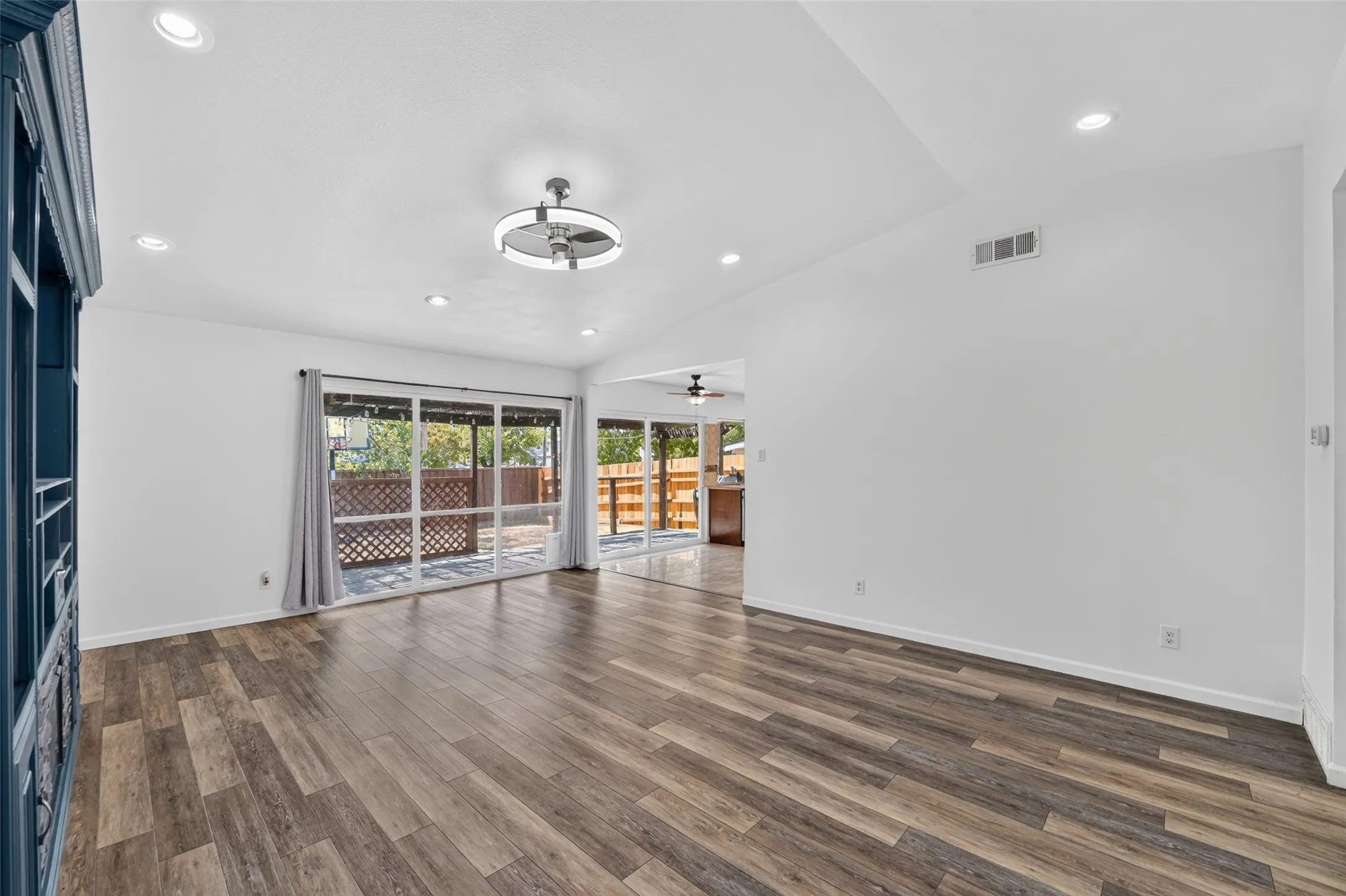 Wood-finish flooring, vaulted ceiling, recessed lighting, modern ceiling fan, and sliding glass doors to outdoor patio