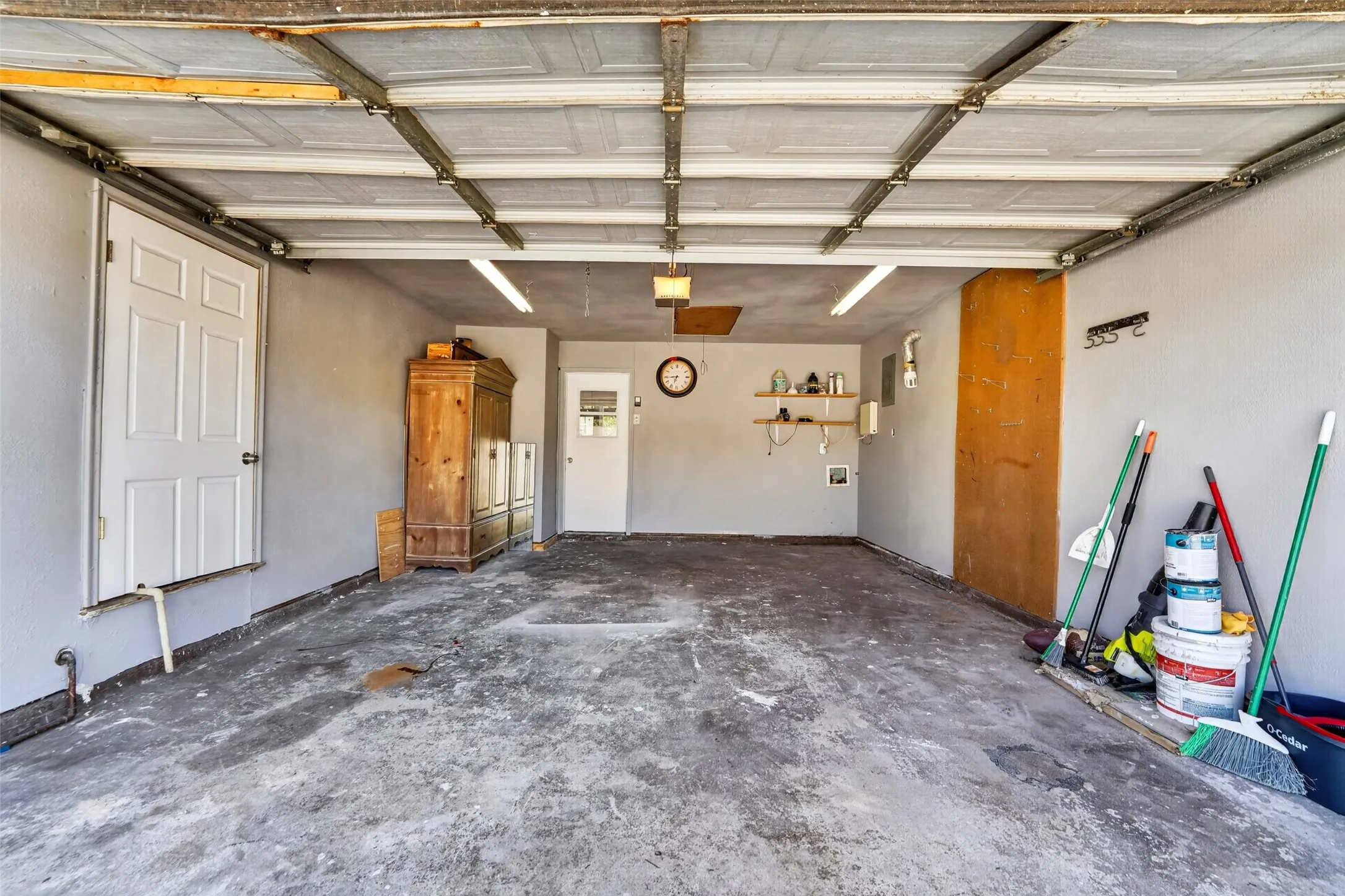 Attached garage with concrete flooring, fluorescent lighting, and multiple entry doors