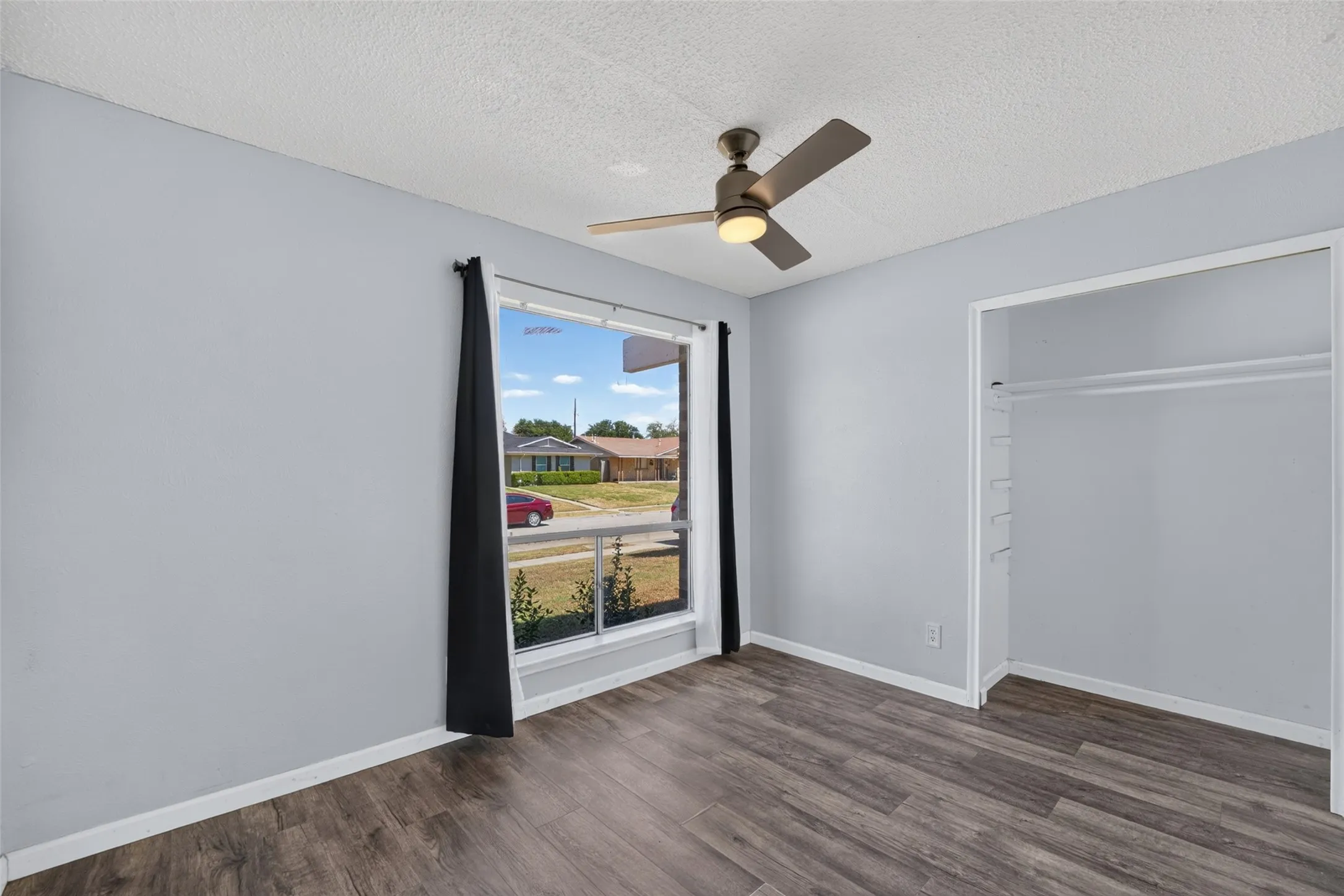 Wood-finish flooring, ceiling fan with integrated lighting, and a window with white trim