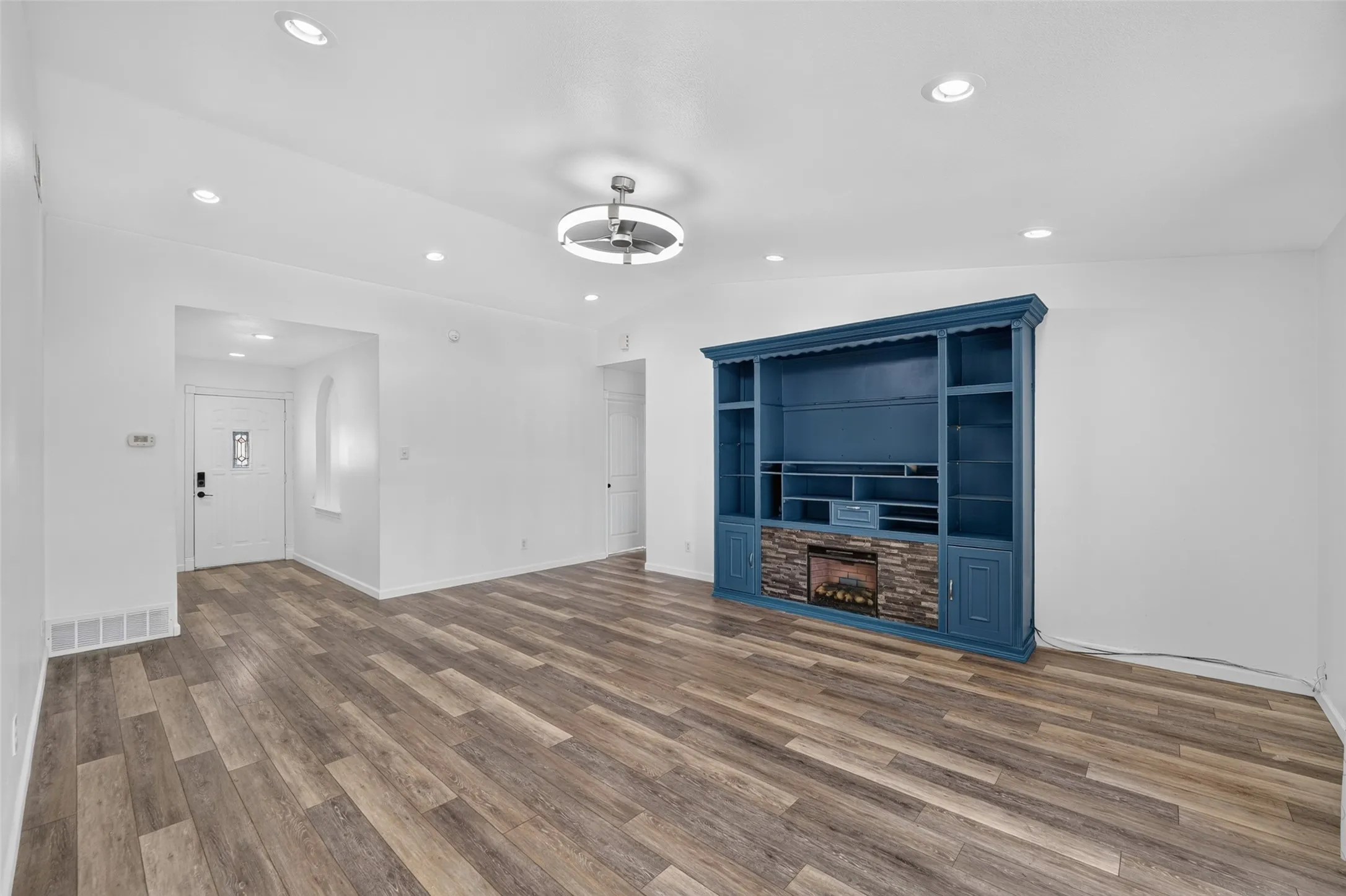 Wood-finish flooring throughout, recessed ceiling lighting, and a modern ceiling fixture