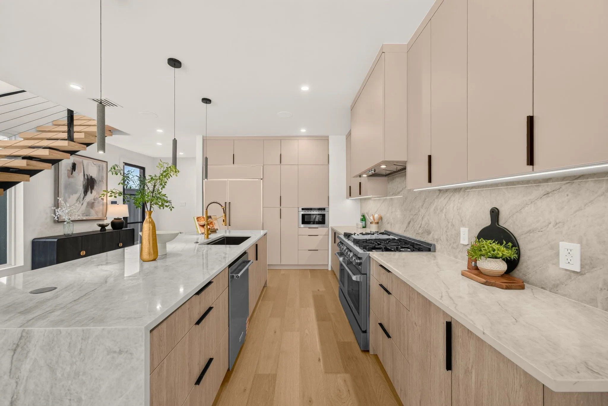 Kitchen featuring an expansive island with a waterfall edge, integrated sink, and modern pendant lighting
