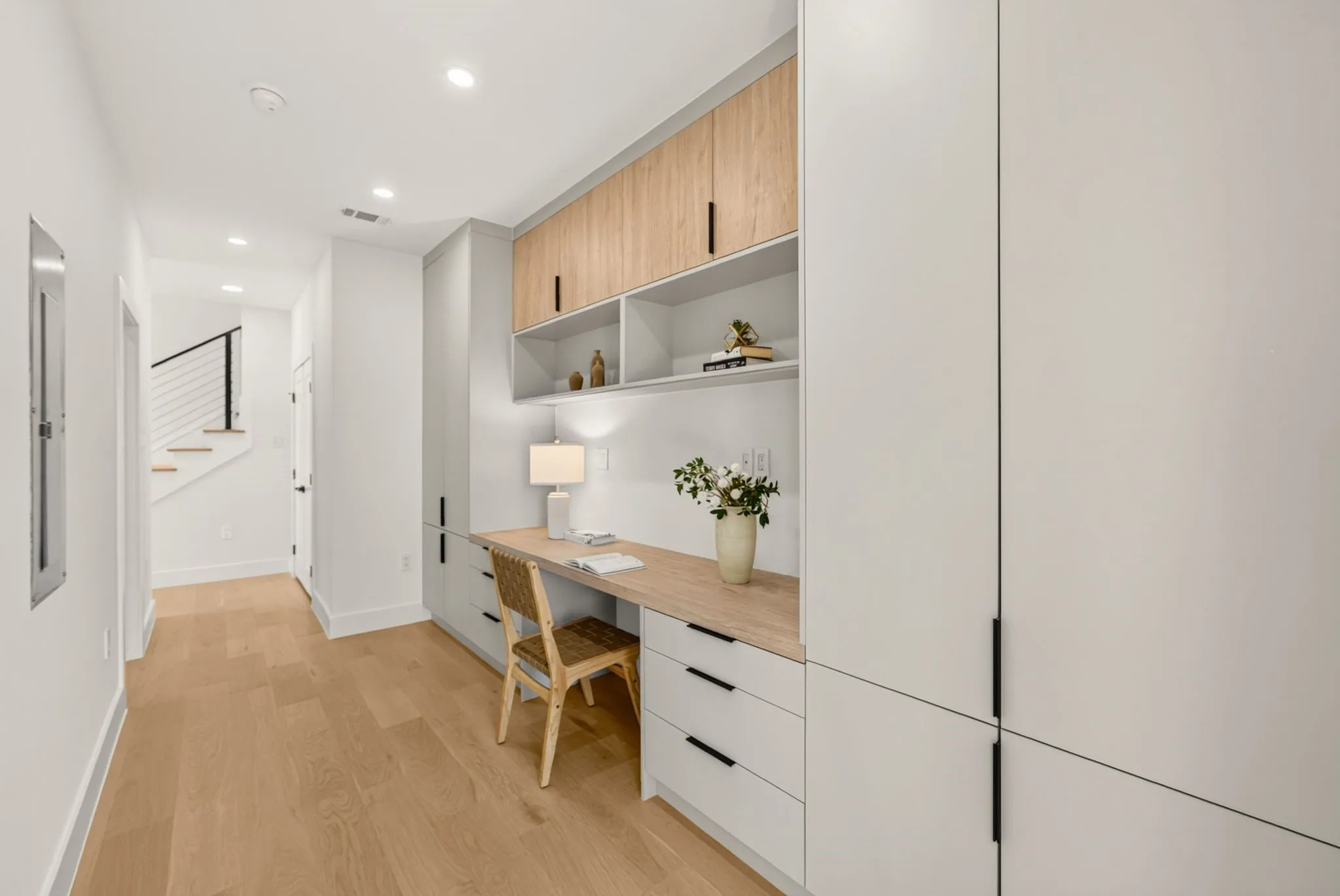 Integrated built-in desk with wood-finish countertop, open shelving, and overhead cabinetry