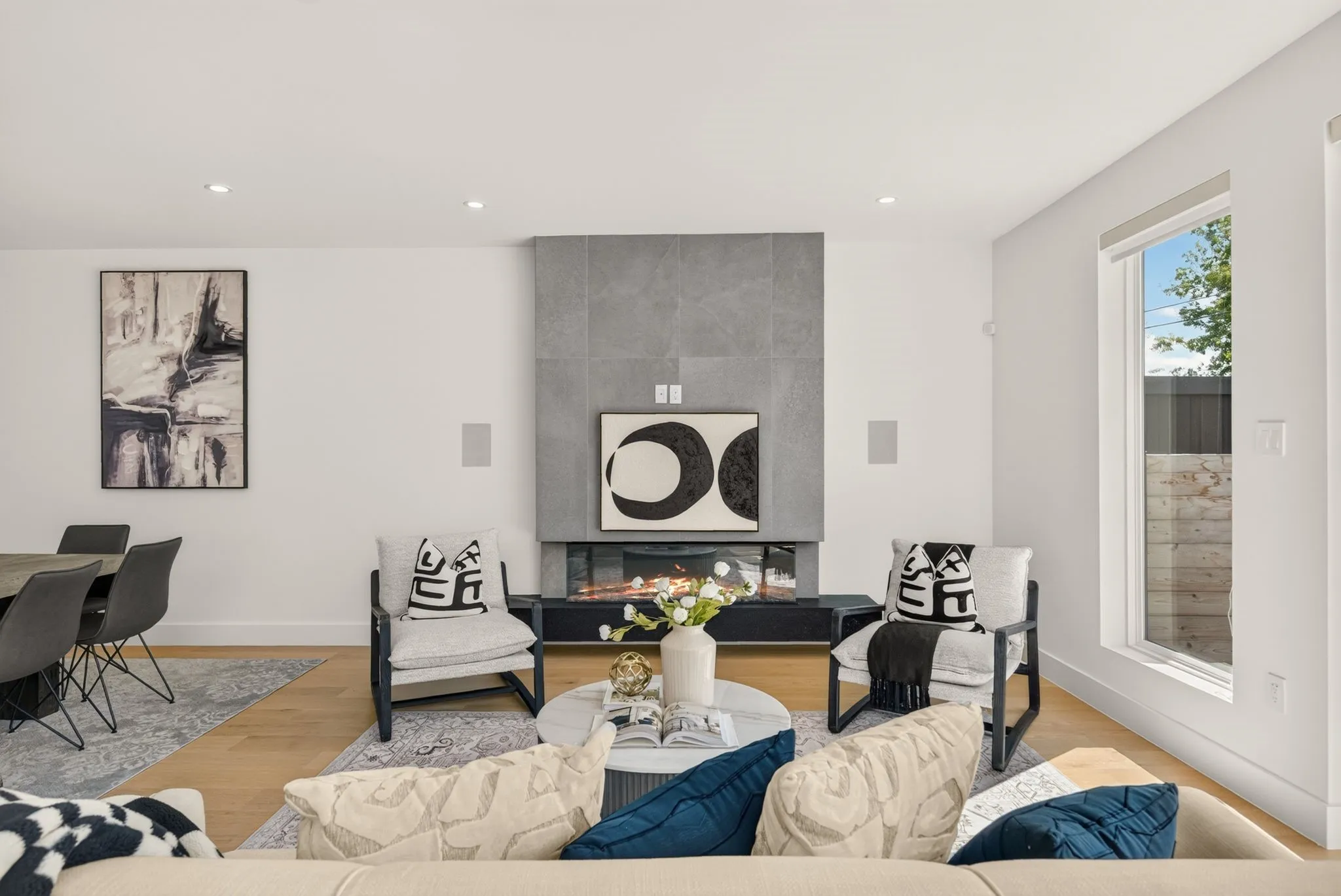Recessed lighting, wood-finish flooring, a contemporary fireplace with a stone surround, and an expansive window