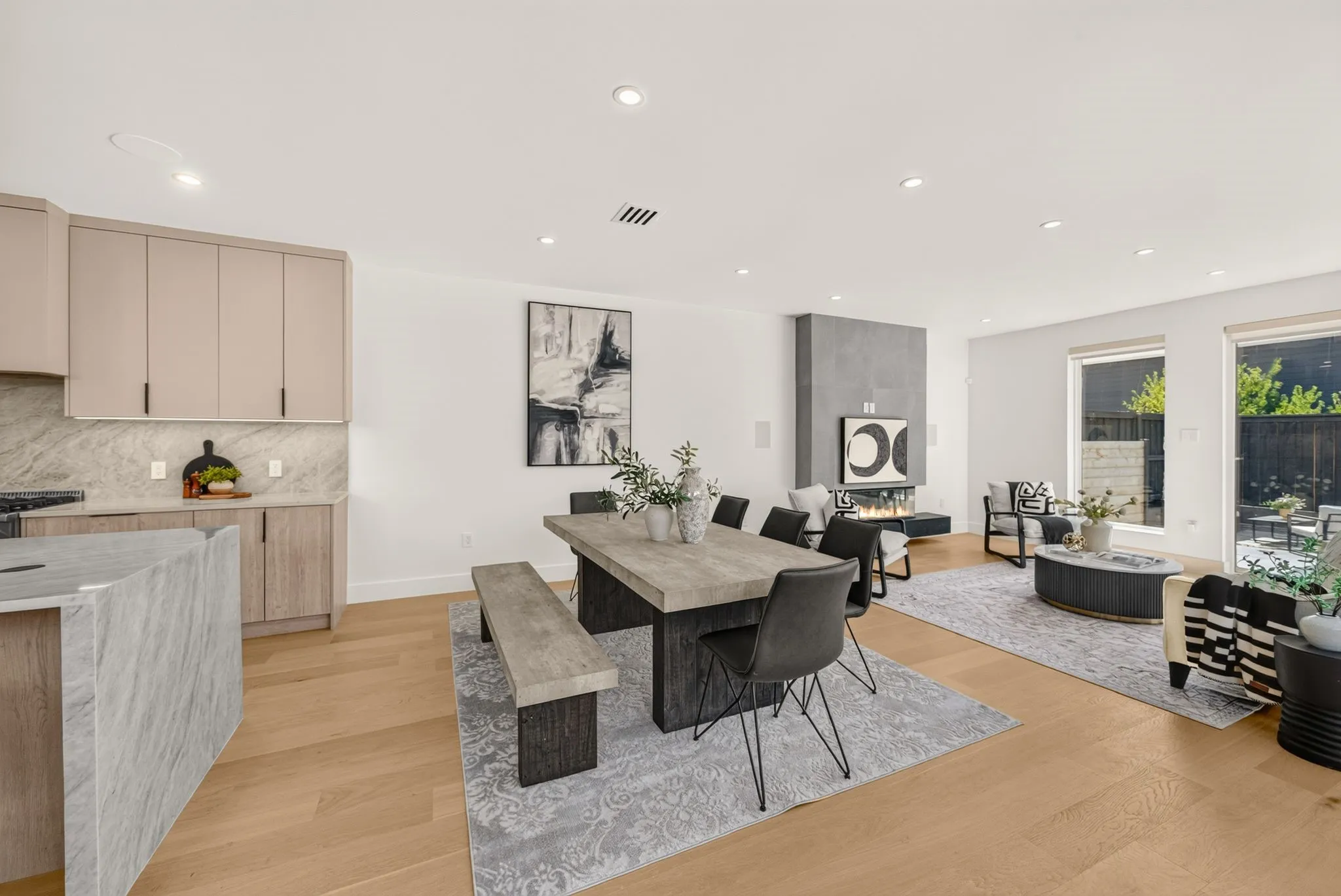 Open-concept living space featuring wood-finish flooring, a modern fireplace, and recessed lighting