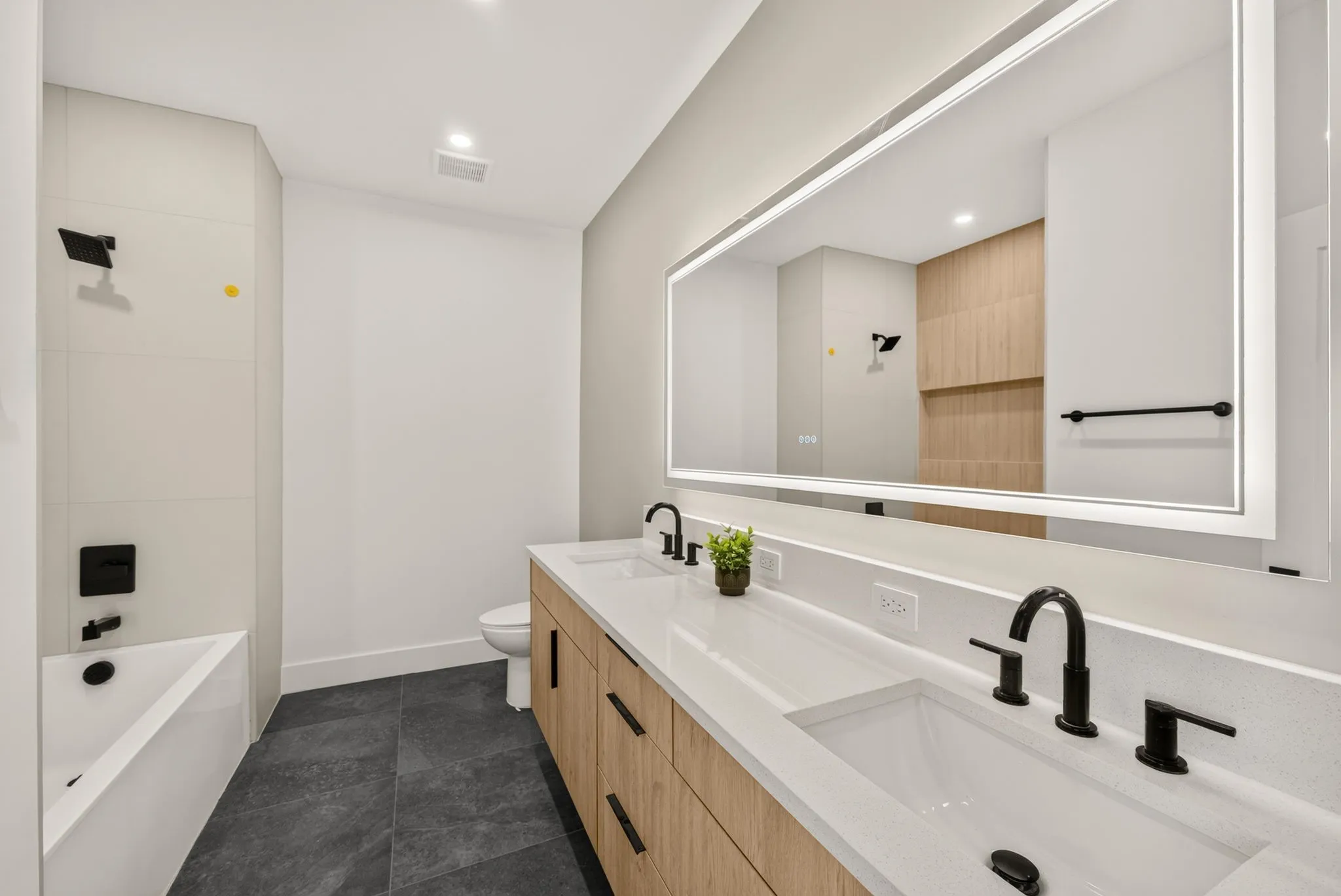 Dual vanity with integrated sinks, wood-finish cabinetry, and matte black fixtures