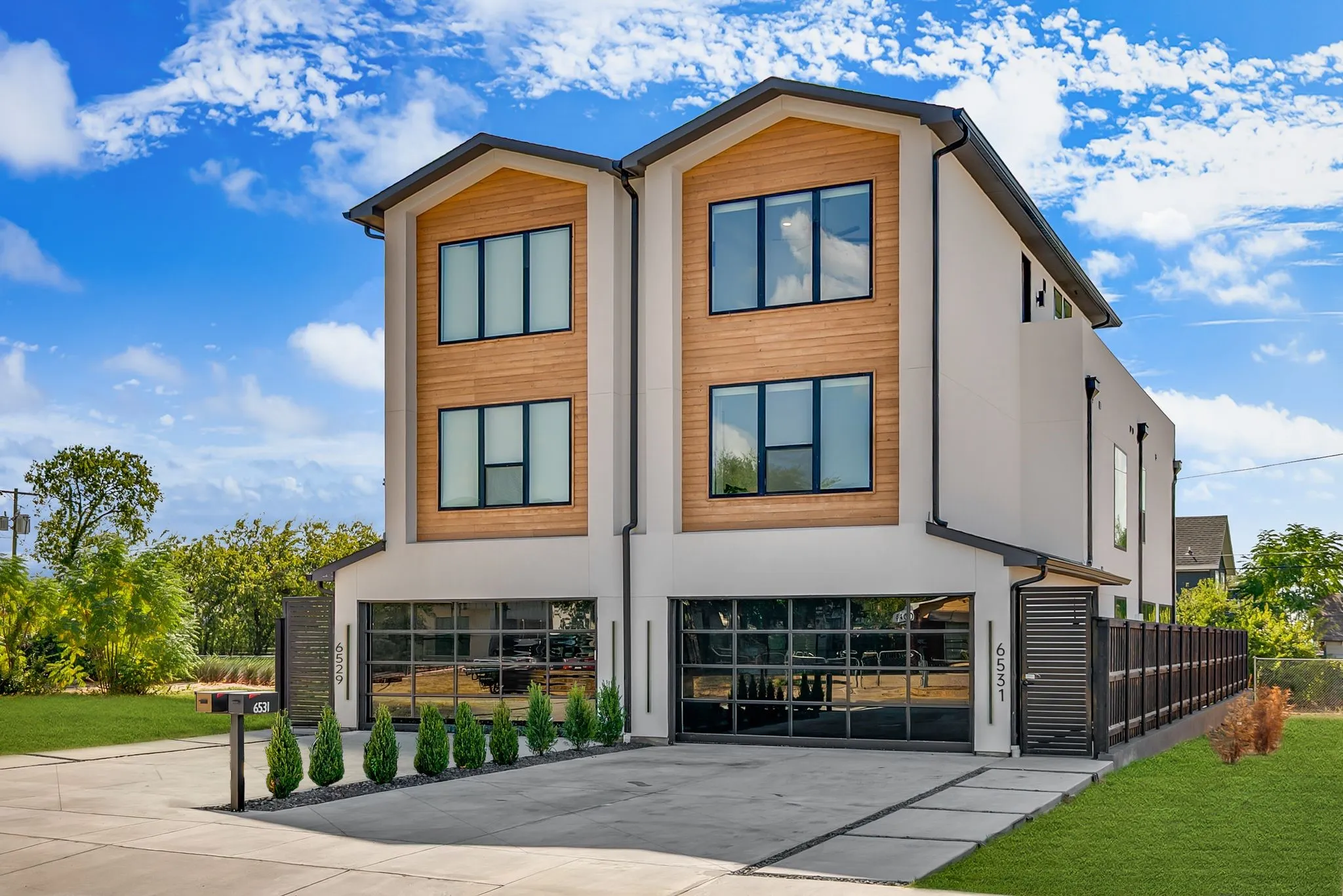 Modern facade with stucco, panorama garage doors, and wood-finish siding