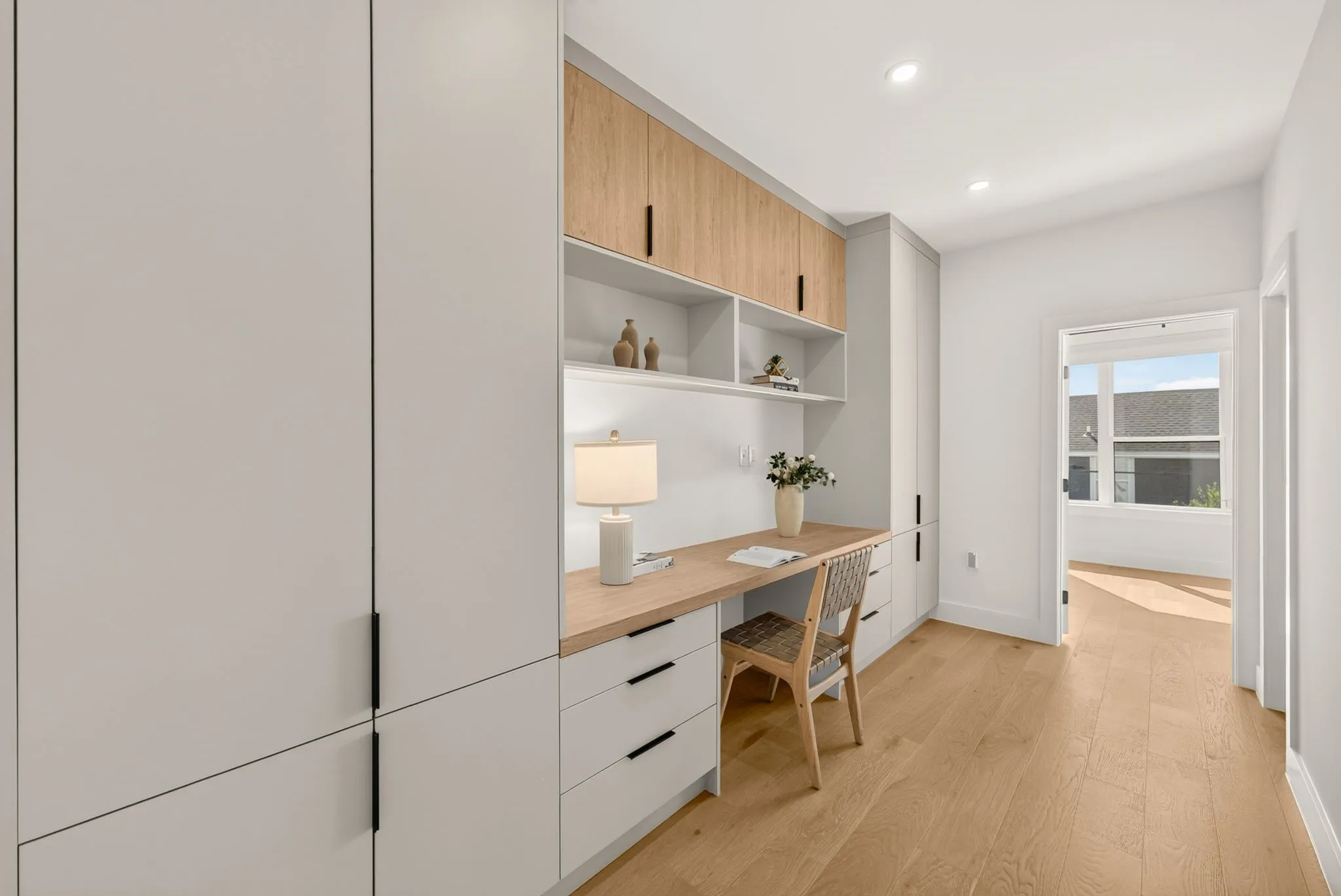 Integrated desk with wood-finish countertop, built-in shelving, and recessed lighting