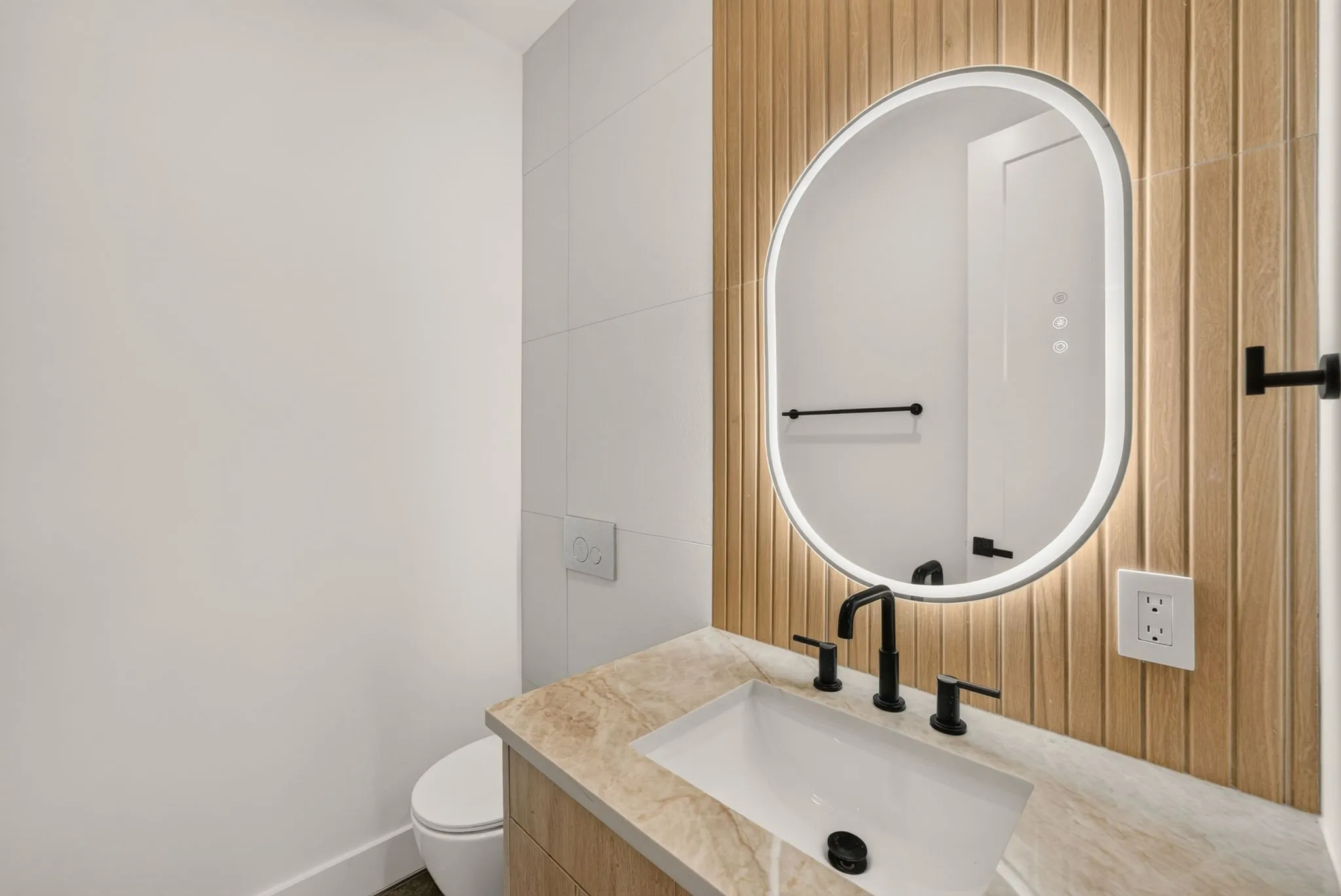 Integrated vanity with a rectangular basin, stone countertop, and matte black fixtures