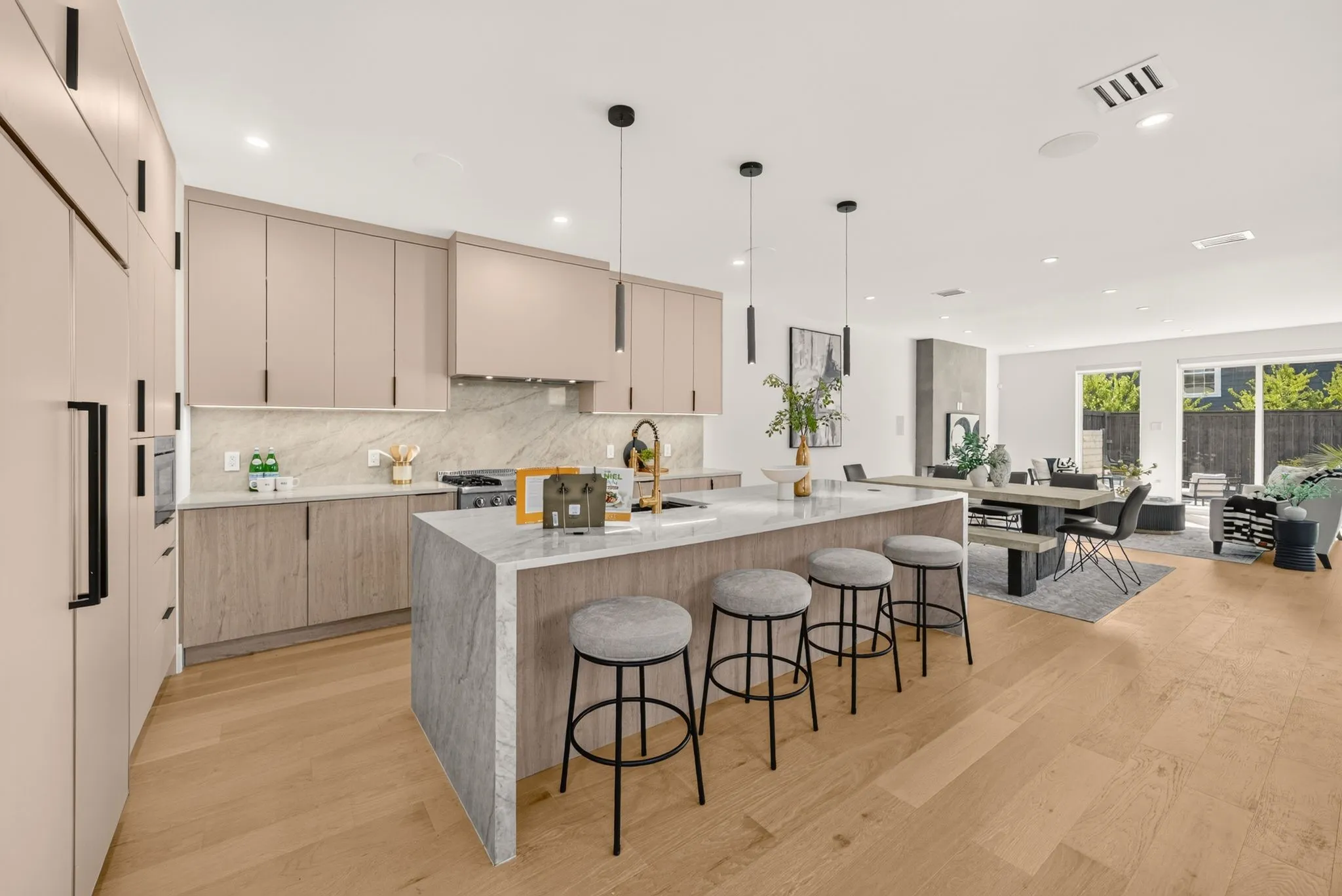 Kitchen featuring a waterfall island, light wood-finish flooring, integrated refrigerator, and pendant lighting