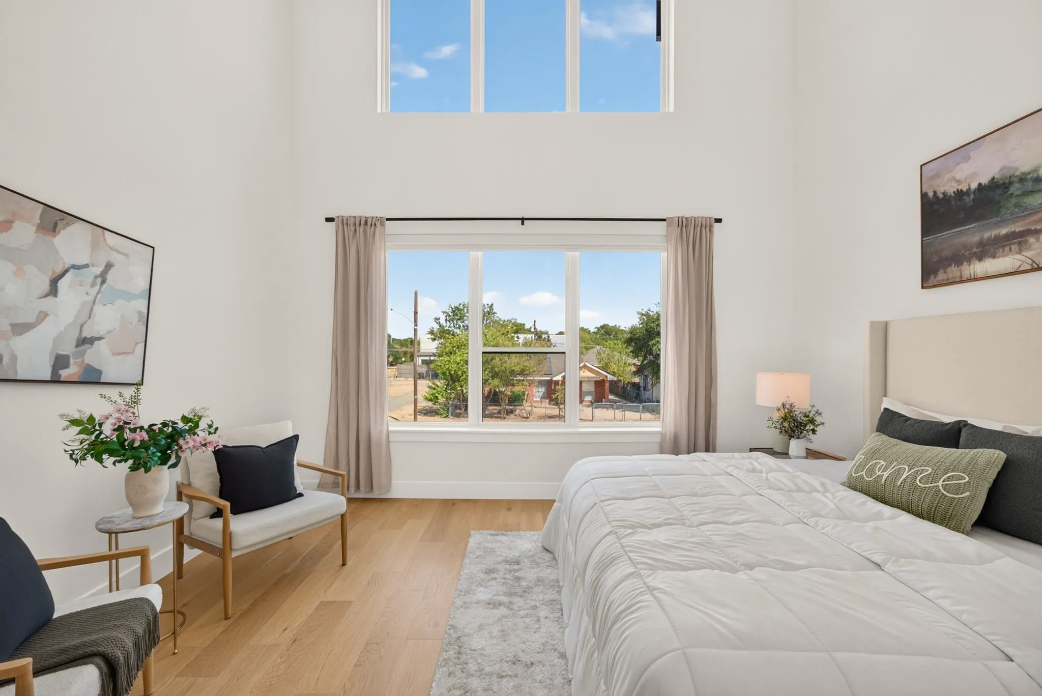 Vaulted ceiling with high transom windows, large main window with natural light, wood-finish flooring, and light-toned walls