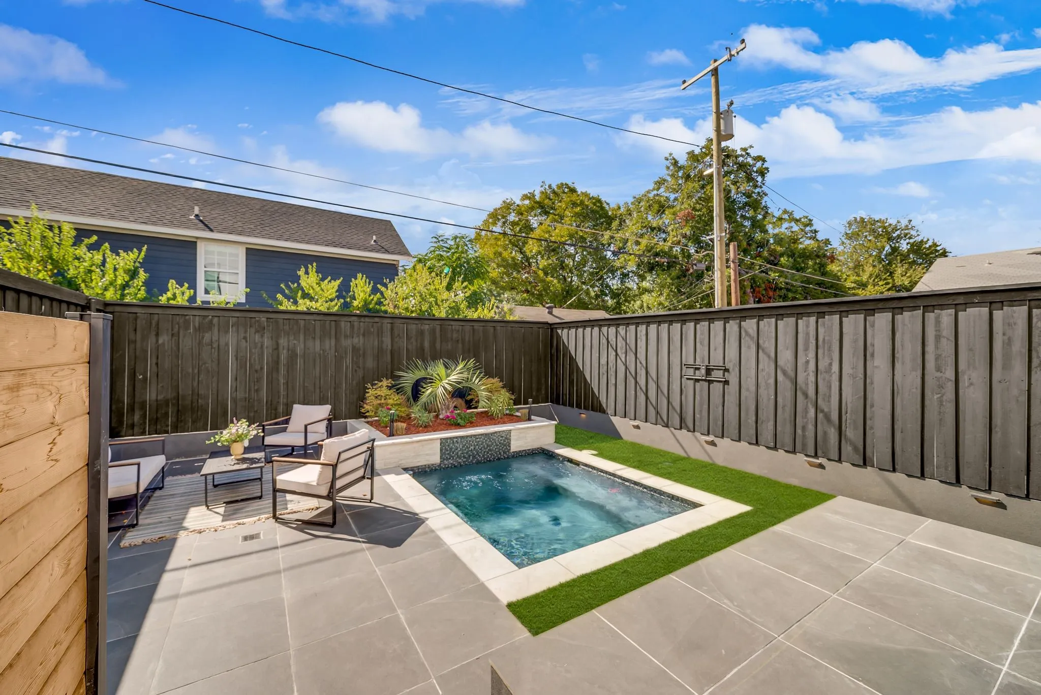 Outdoor patio with large format pavers, a built-in plunge pool with tile surround, and a raised planter bed