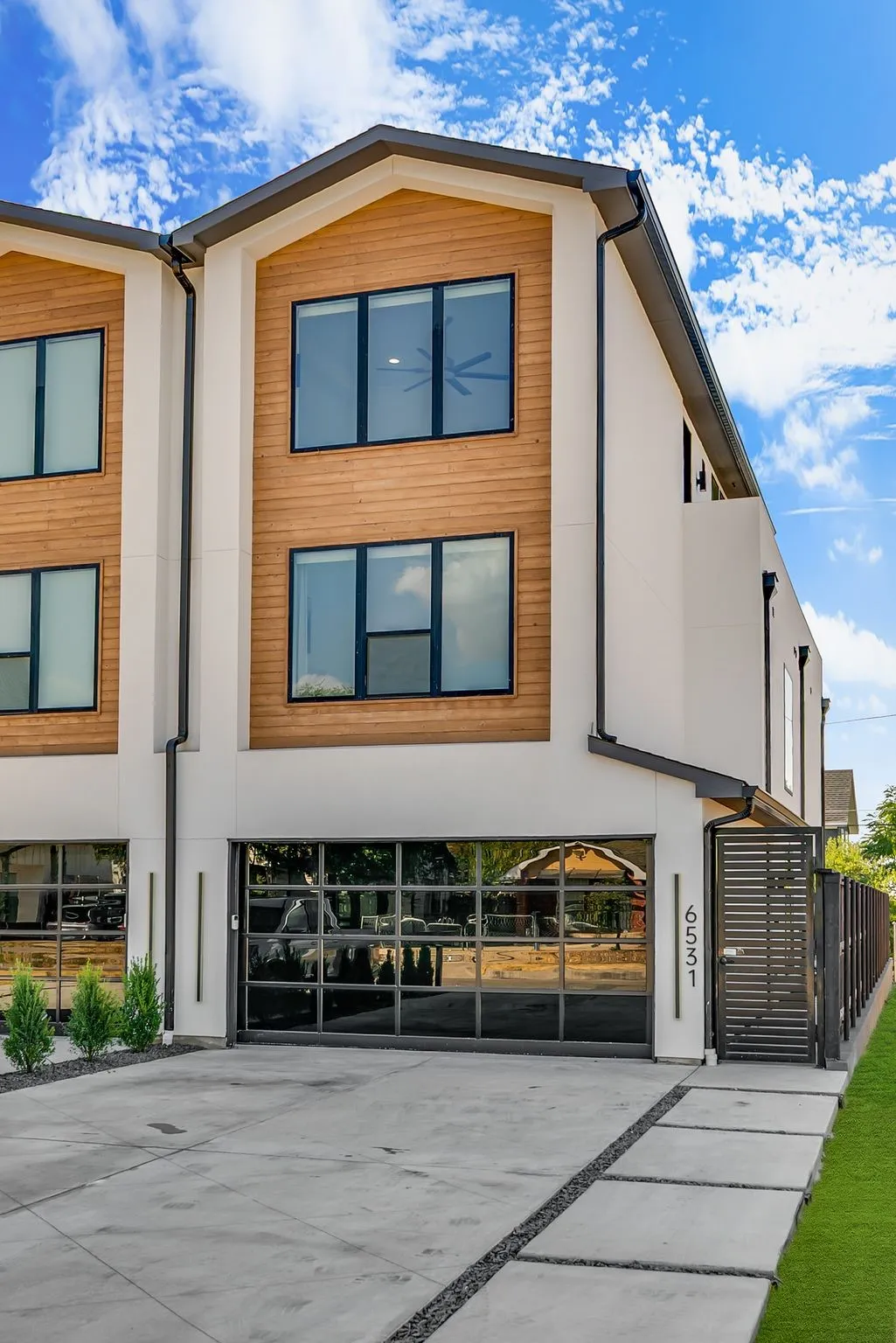 Modern facade featuring light-colored siding and wood-finish paneling