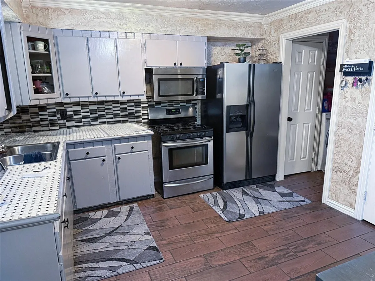 Kitchen workspace highlighting stainless steel side-by-side refrigerator, built-in microwave, and range oven.