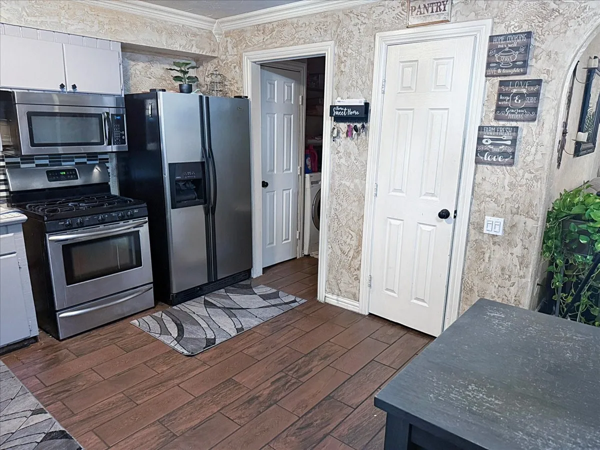 Kitchen view showing pantry storage area, side entry access door, and continuous tile flooring.