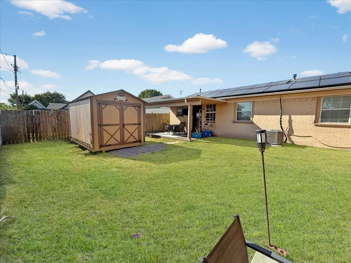Rear exterior elevation showing back patio area, roofline solar panels, and detached storage shed.