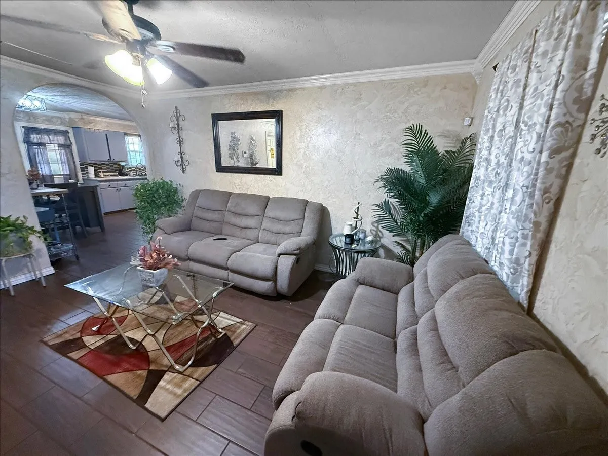Spacious family living room featuring dark tile flooring, ceiling fan, and generous space for sectional seating.