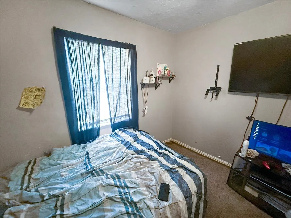 Comfortable bedroom view featuring window drapes, ceiling fan, and neutral finishes.