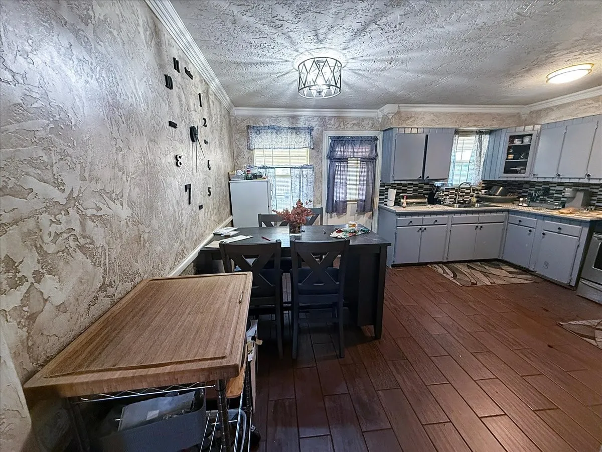 Open dining area transition adjacent to the kitchen with dark flooring and overhead lighting.