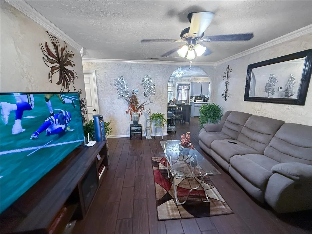 Living room alternate perspective displaying wall-mounted TV setup, open layout, and bright ceiling lighting.