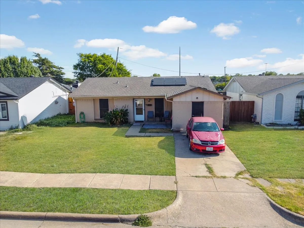 Street-level front elevation highlighting solar panels, front entry, and mature neighborhood surroundings.