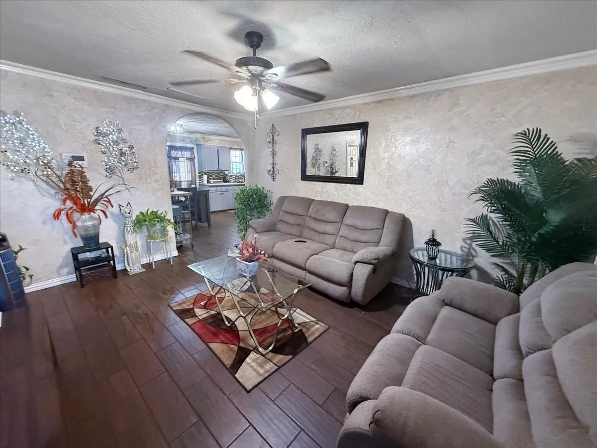 Spacious flex living zone displaying plush seating, ceiling fan, and decorative wall finishes.