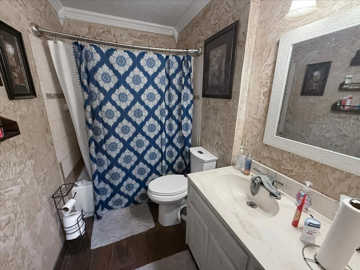 Full bathroom equipped with a white vanity cabinet, framed mirror, and tub/shower combination with decorative tile.