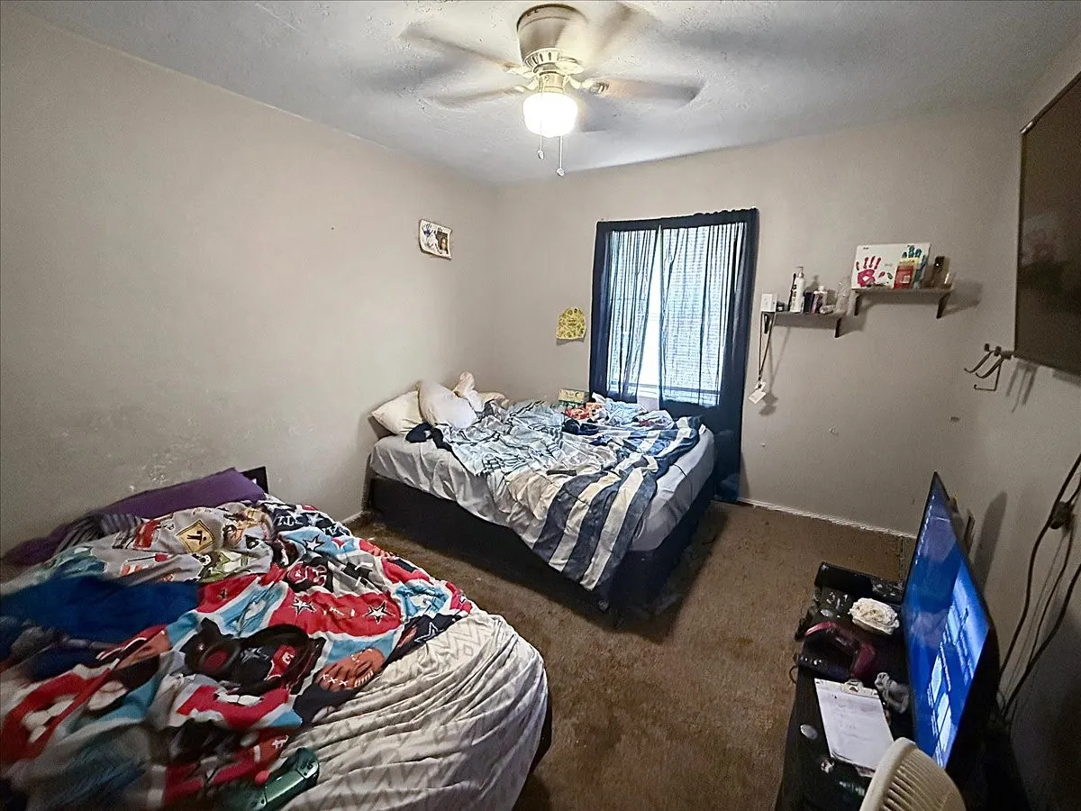 Secondary bedroom featuring overhead ceiling fan, neutral walls, and twin bed arrangements.