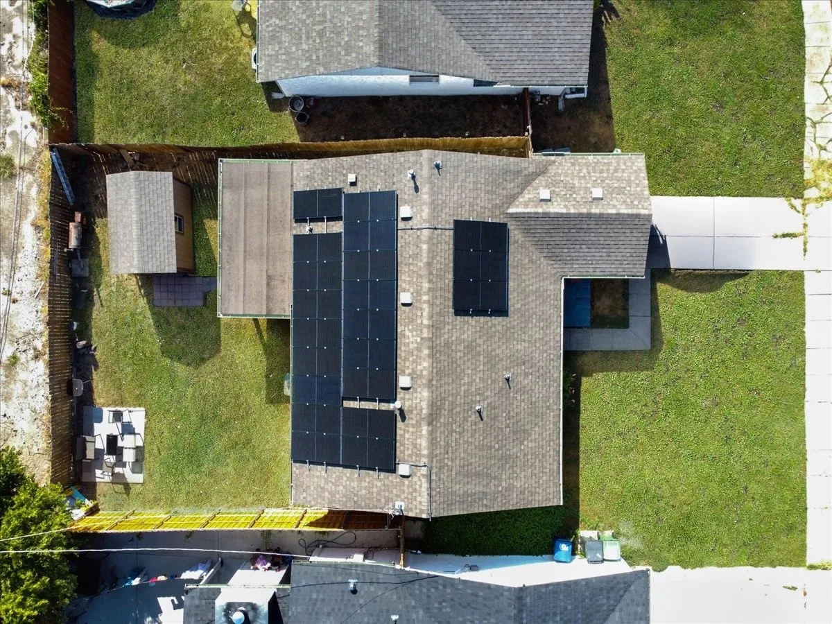 Direct overhead top-down aerial shot showcasing the complete property lot, roofline solar array, and yard.