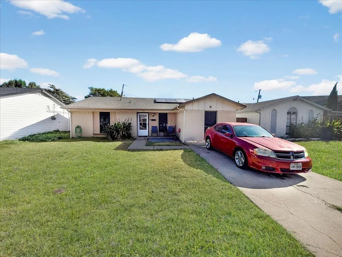 Street-level front elevation showcasing the wide driveway approach, attached carport, and quiet neighborhood setting.