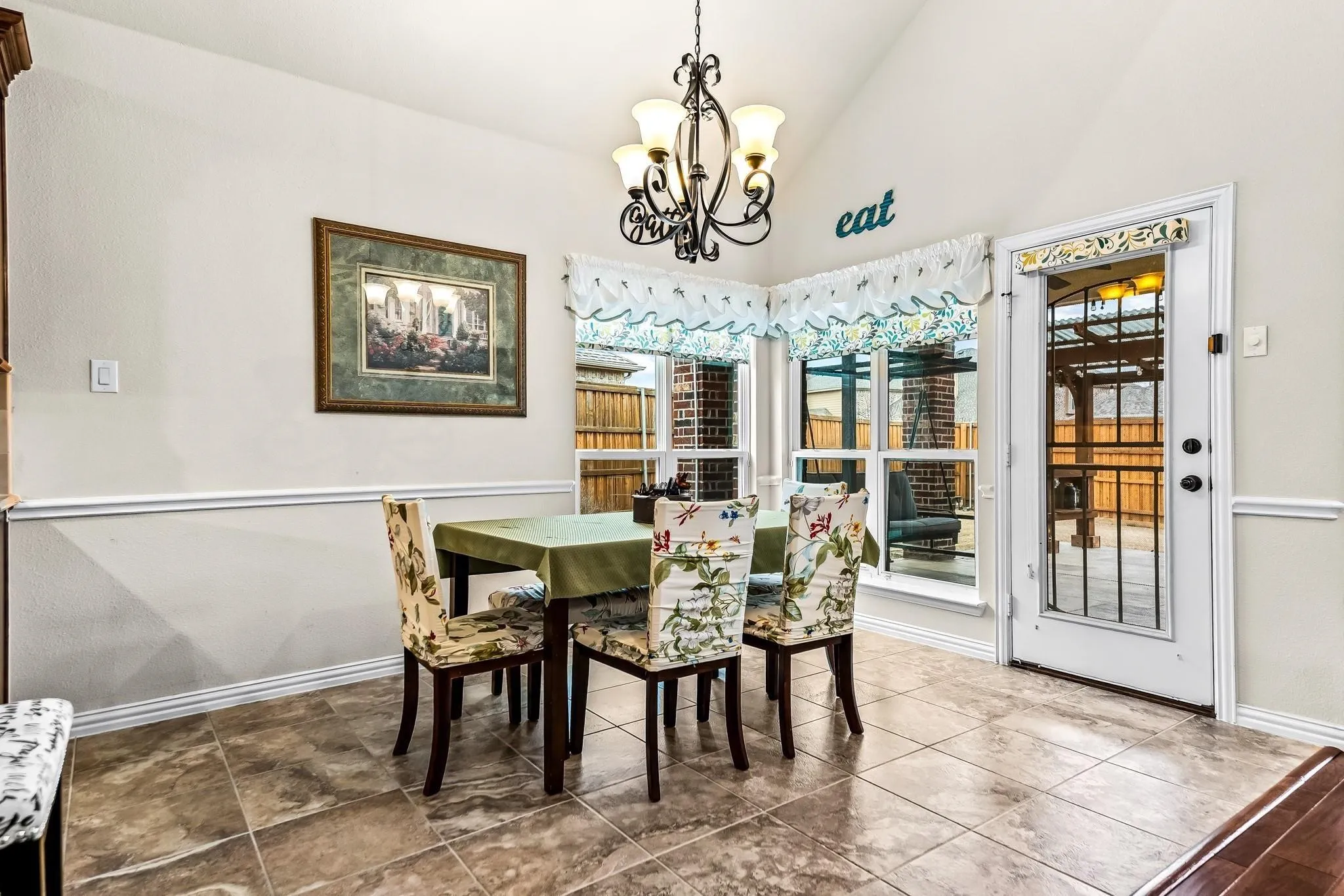 Vaulted ceiling, decorative chandelier, bay windows, glass-paneled door, and tile flooring