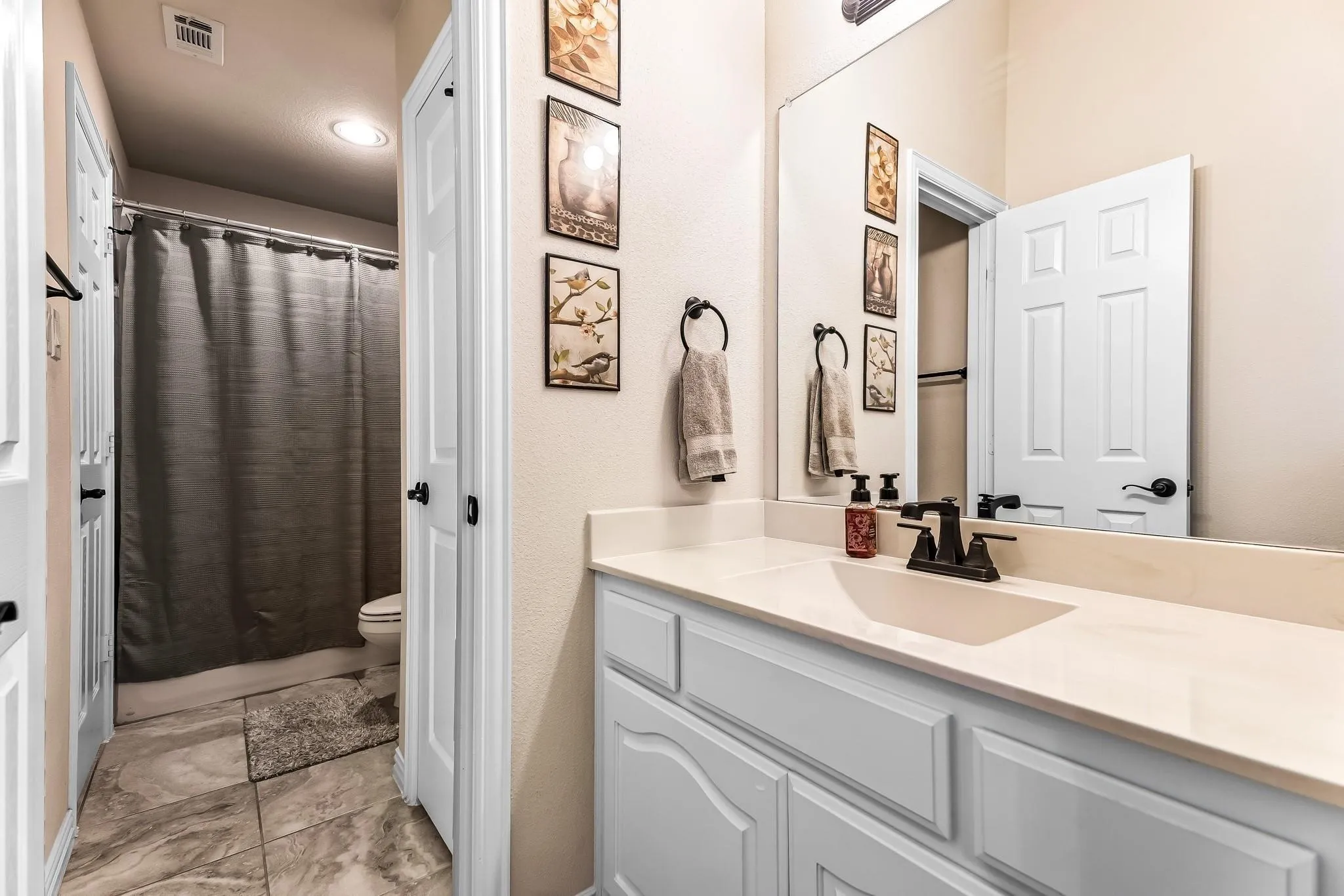 Single vanity with integrated sink, white cabinetry, light-toned countertop, and matte black faucet