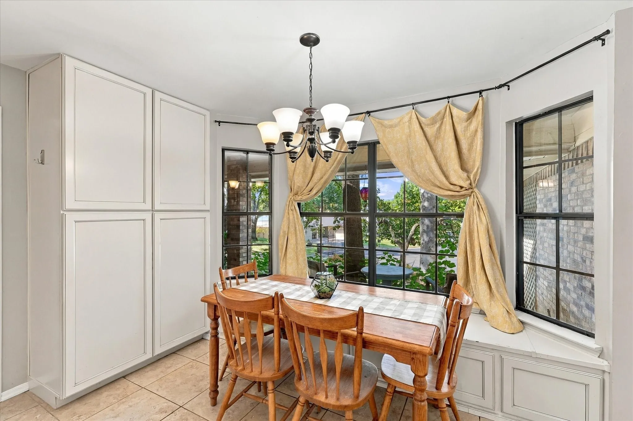 Bay window with built-in bench seating, multiple grid-pattern windows, and a ceiling-mounted chandelier