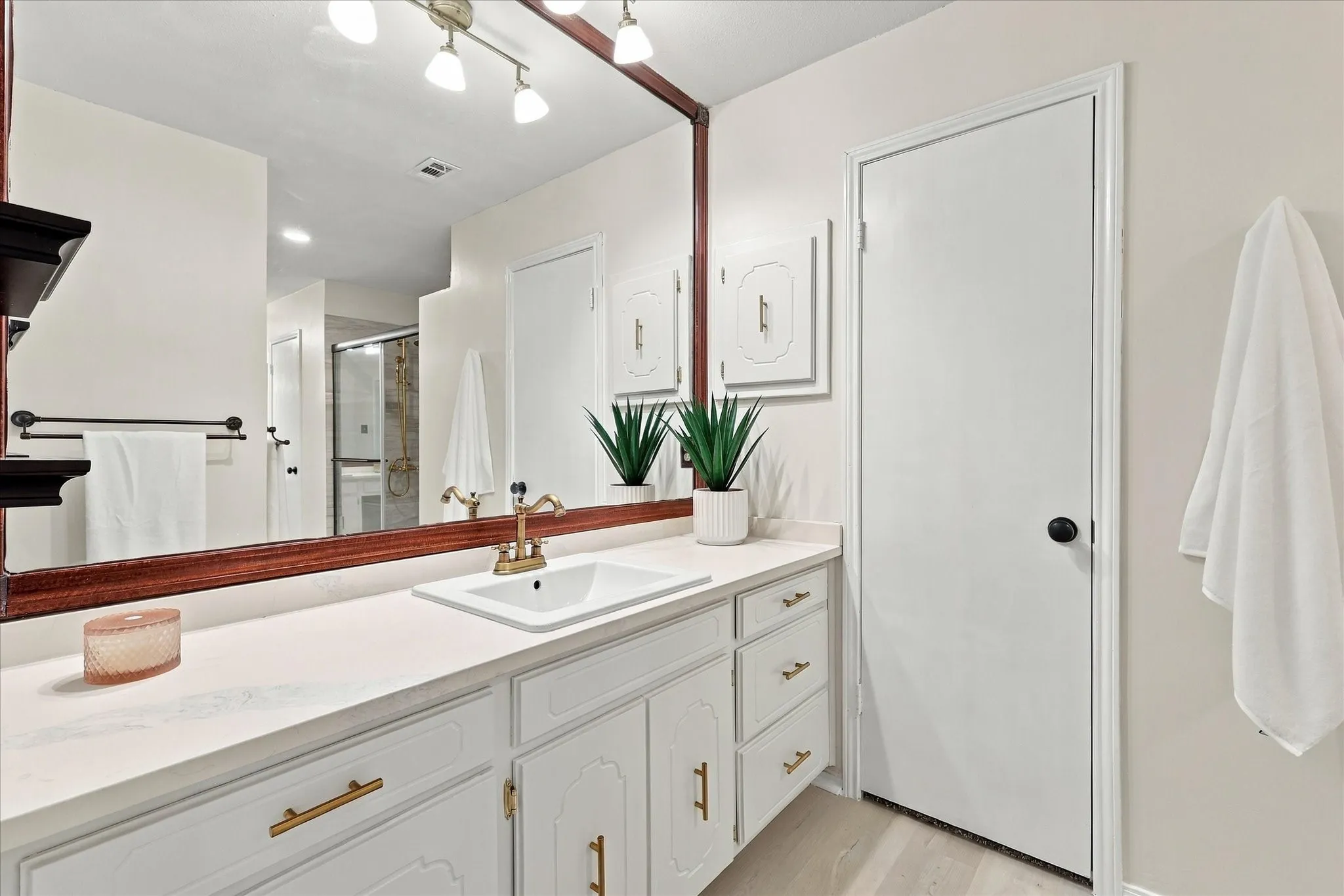 White vanity with a rectangular undermount sink, gold-tone faucet, and white countertop