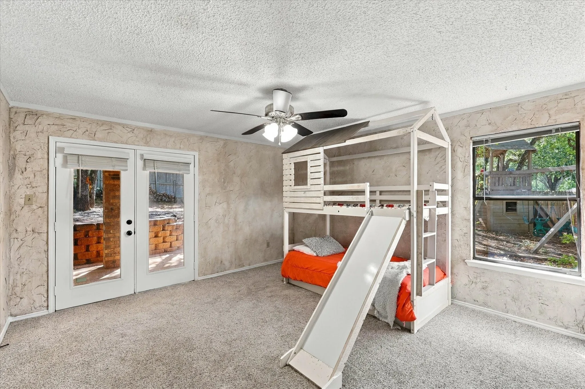 Wall-to-wall carpeted flooring with a ceiling fan, French doors, and a window providing exterior views