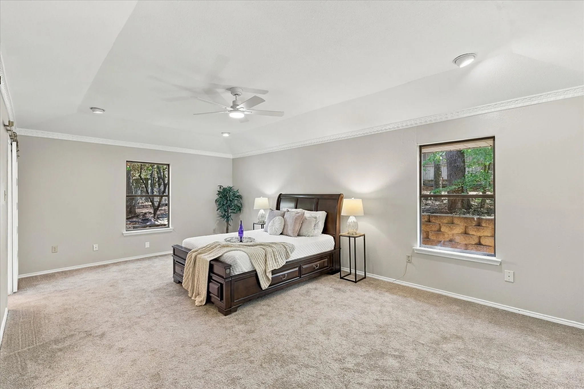 Recessed ceiling with ceiling fan, crown molding, and dual windows